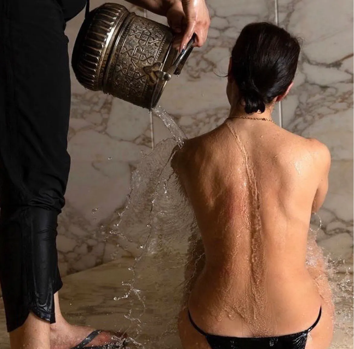 A copper bucket in use during an authentic hammam ritual