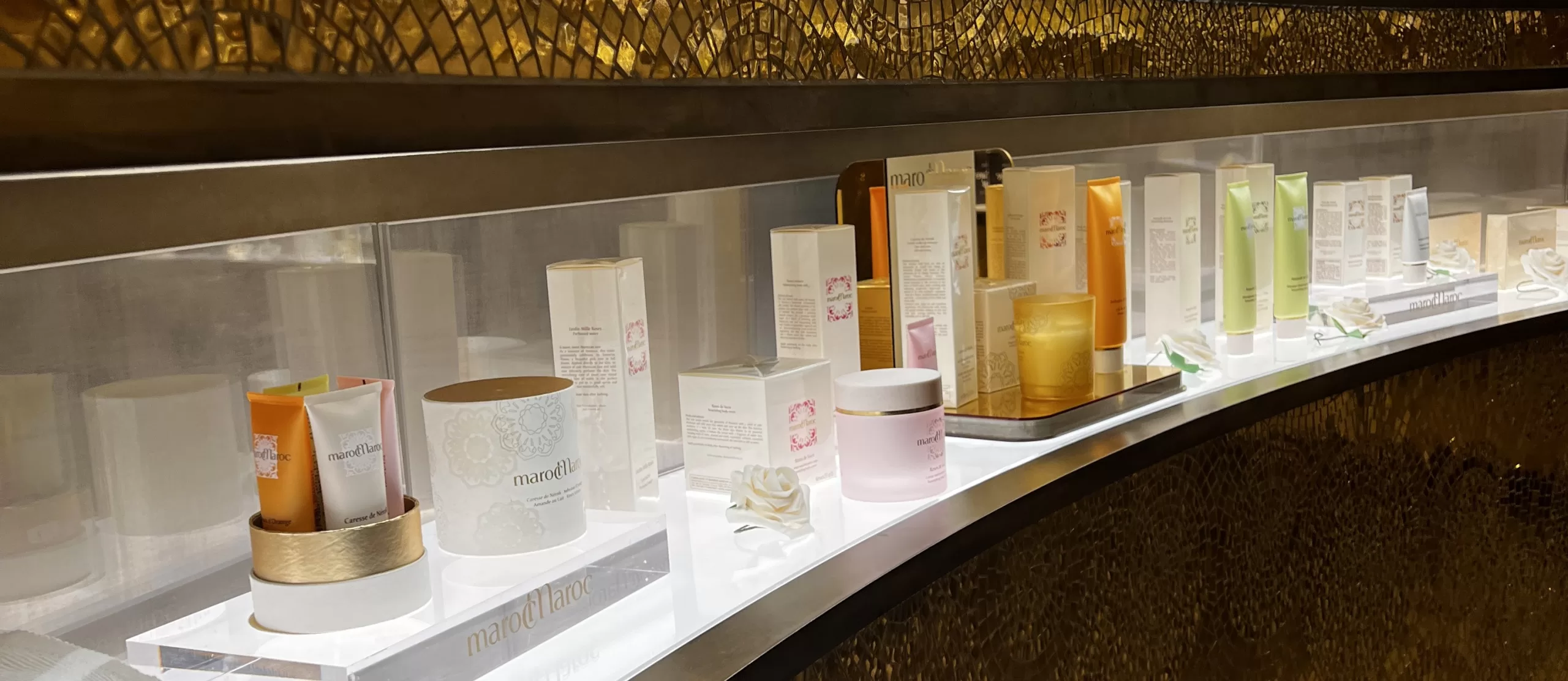 Illuminated marocMaroc retail shelf curving along a gold mosaic wall