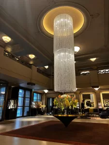 Hotel Café Royal lobby with sculptural crystal chandelier, floral centrepiece and reception in the background